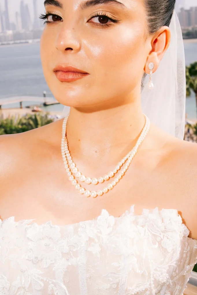 Close-up of the bride wearing a pearl necklace with the city skyline behind