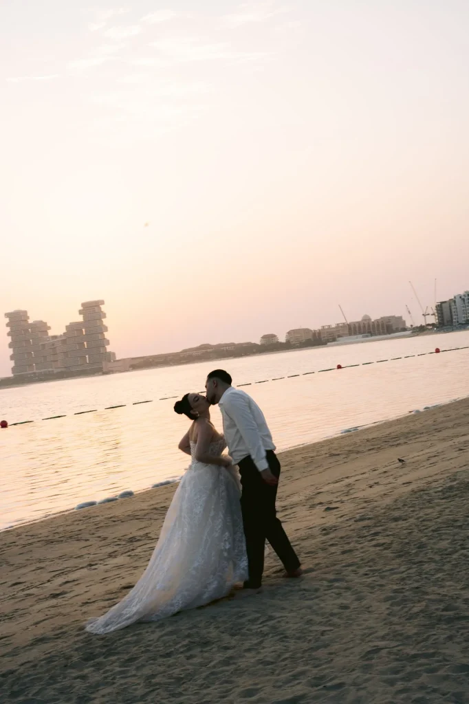 Bride and groom kissing on the beach at sunset