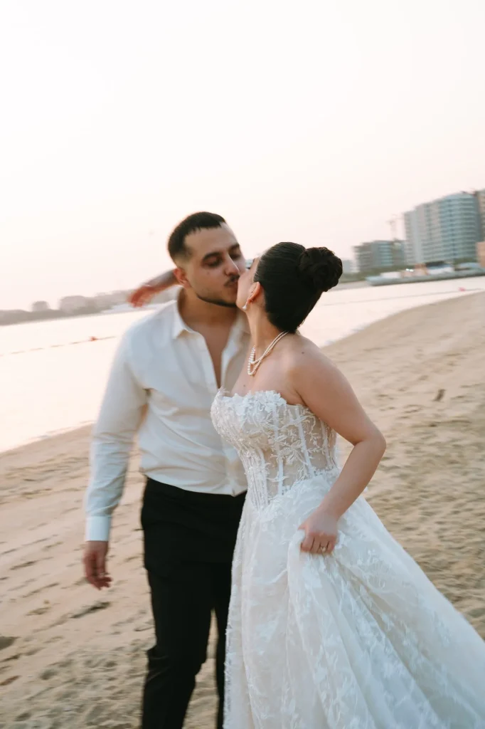 Groom kissing the bride on the cheek on the beach