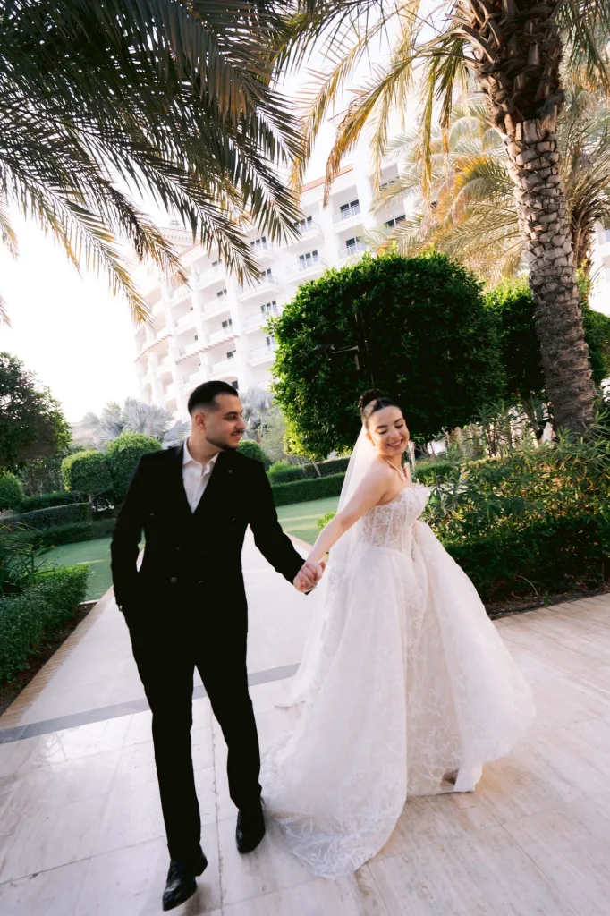 Bride and groom walking hand in hand through a hotel garden