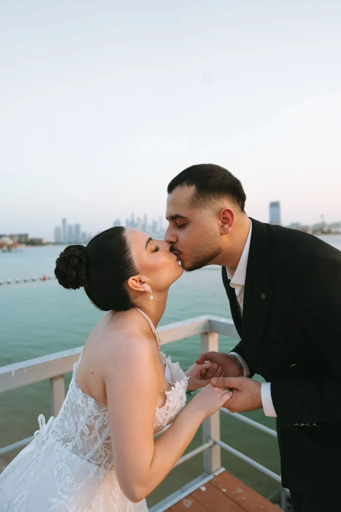 Bride and groom kissing on a balcony above the sea