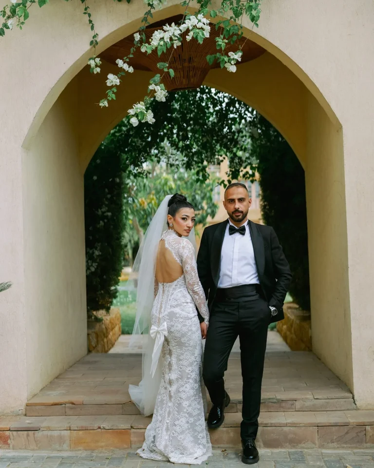 Bride and groom standing under a garden archway