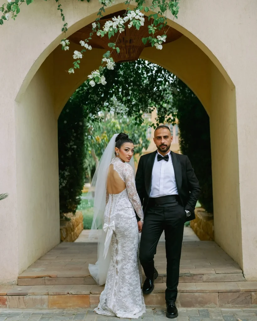 Bride and groom standing under a garden archway