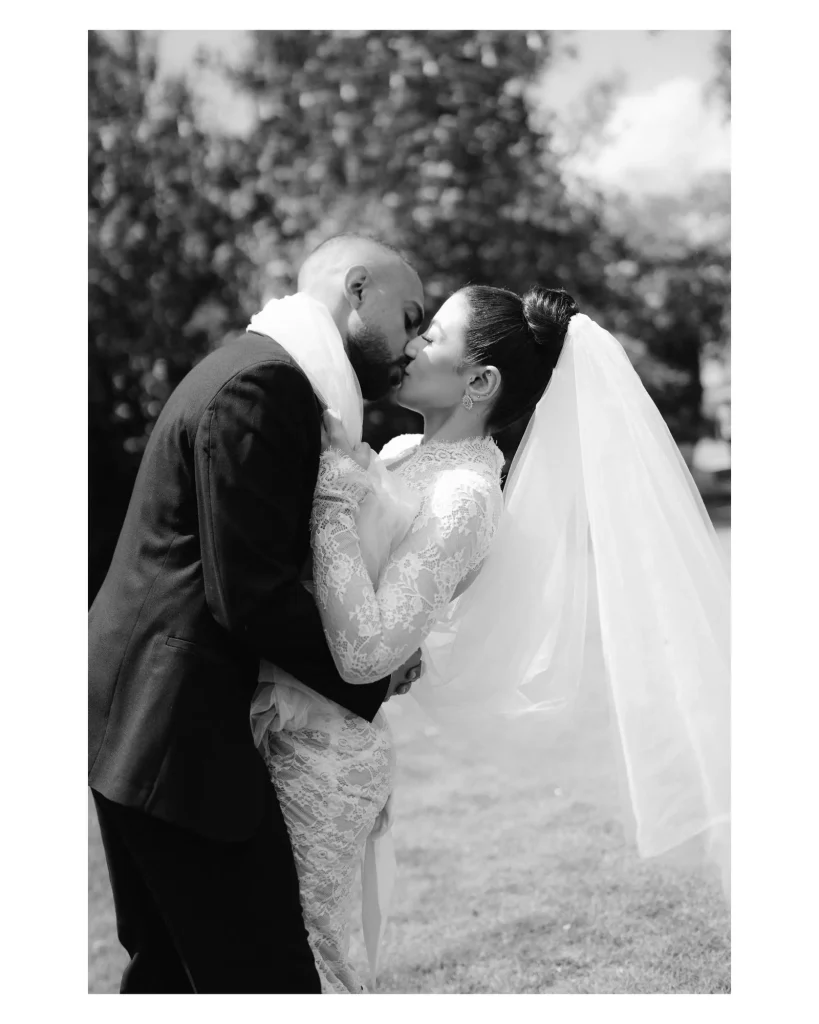 Black and white photo of the groom kissing the bride under her veil