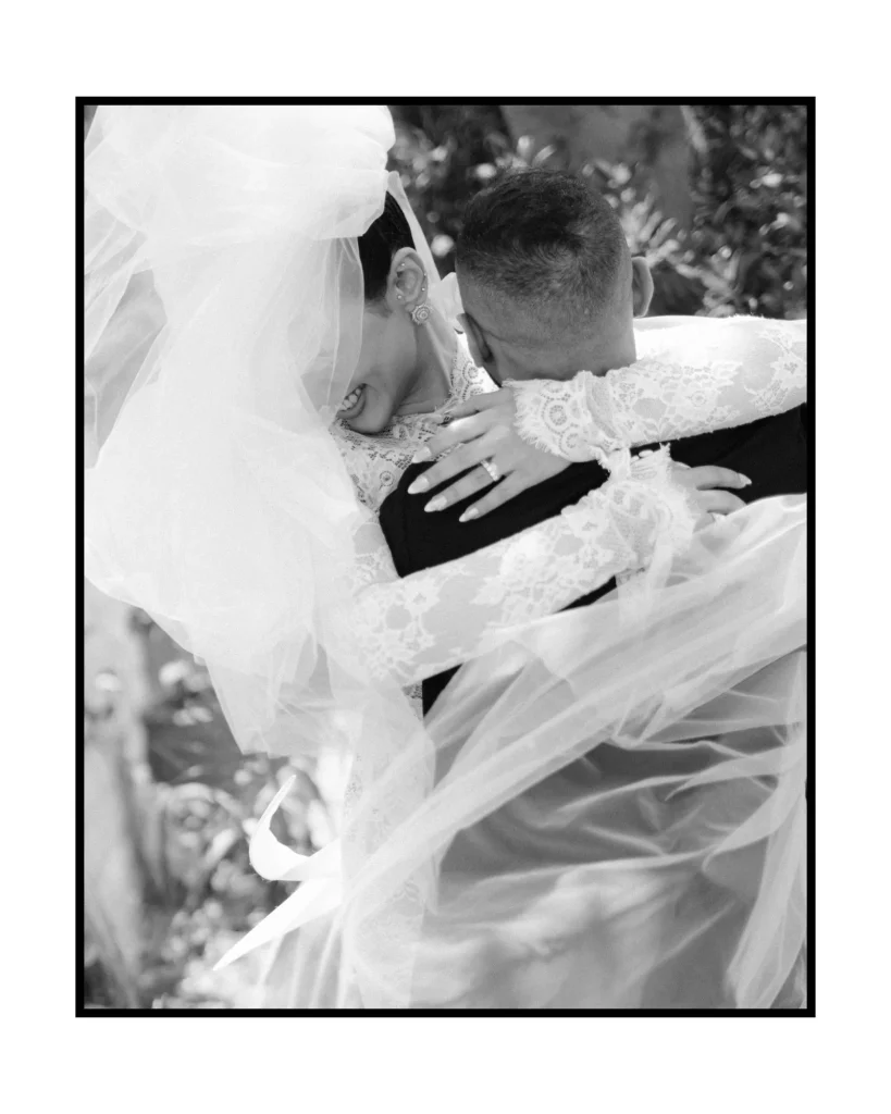 Black and white embrace with the bride’s veil in the wind
