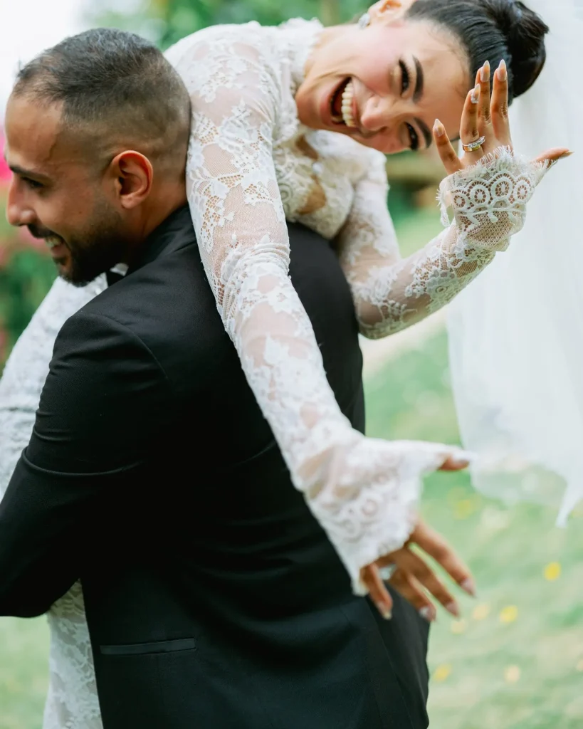 Bride laughing as she leans over the groom’s shoulder