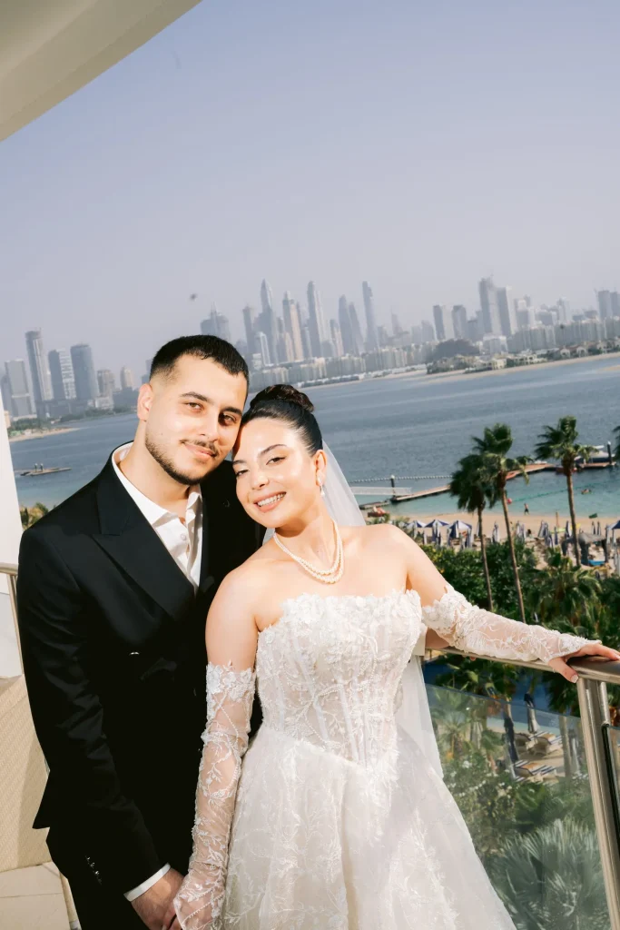 Bride and groom on a balcony overlooking the sea and city skyline