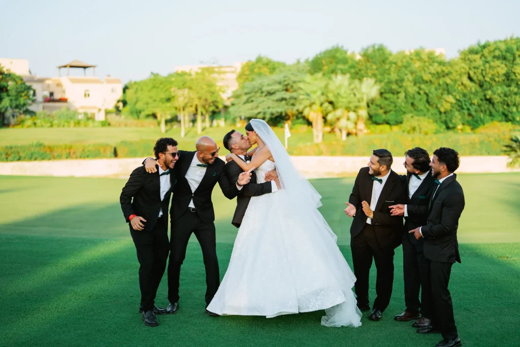 Bride and groom celebrating with the groomsmen on a lawn