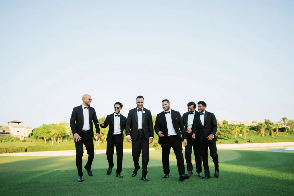 Groom and groomsmen walking together across a lawn