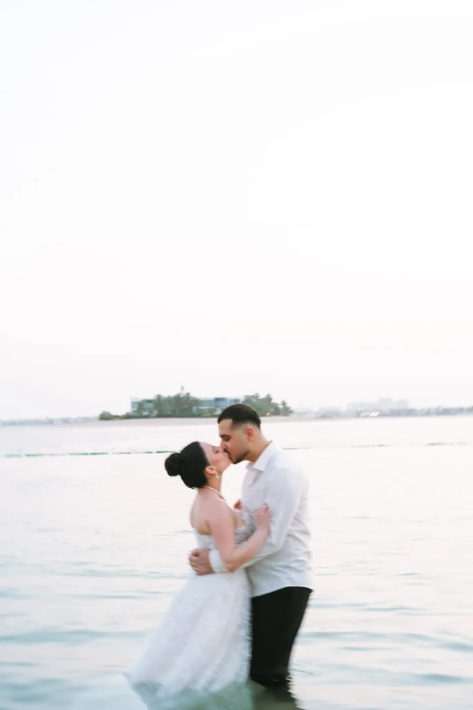 Bride and groom kissing in the sea at sunset